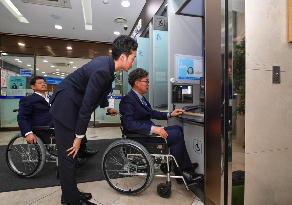 장애인식 개선 교육에 직접 나선 이대훈 농협은행장(오른쪽)이 직접 휠체어를 타고 자동화기기 이용 시연을 하고 있다.