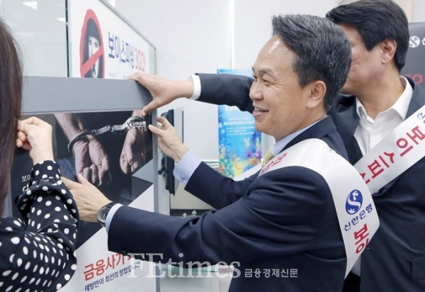 지난해 6월 서울 중구 신한은행 본점에서 열린 '보이스피싱 피해 근절 캠페인'에 참여한 진옥동 은행장이 게시판에 금융사기 피해예방 안내 포스터를 붙이고 있다.(사진=신한은행 제공)