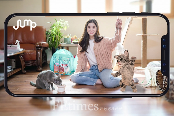 SK텔레콤 홍보모델이 스마트폰으로 실제 고양이와 AR 동물을 함께 촬영하고 있다. 애묘인라면 누구나 점프 AR 앱으로 고양이와 AR 동물을 함께 촬영해 SNS에 공유하면 애묘용품을 추첨 제공받을 수 있다.